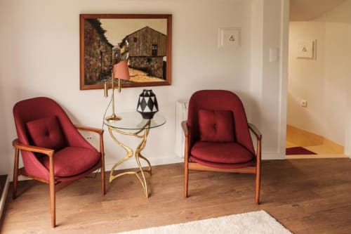 Área de estar da Junior Suite na Quinta de Anterronde com cadeiras retrô vermelhas, mesinha lateral e quadros emoldurados com vista para o