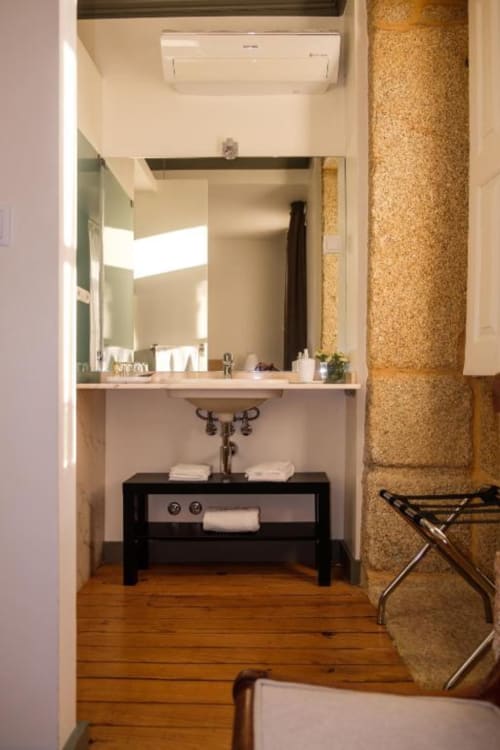 Banheiro moderno com marcenaria preta, espelho amplo e piso de madeira na boutique hotel Quinta de Anterronde em Arouca,