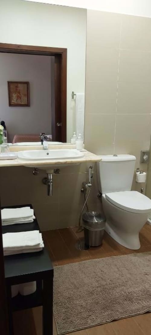 Banheiro moderno na Suíte Tripla da Quinta de Anterronde Superior, Arouca, com pia branca, sanitário, azulejos bege, espelho e