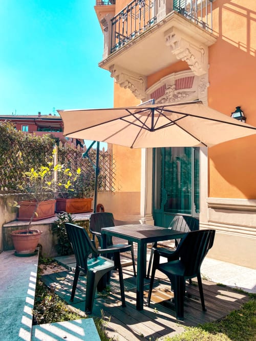 Terrazza soleggiata dell'appartamento Liberty a Verona con tavolo nero, sedie e ombrellone beige