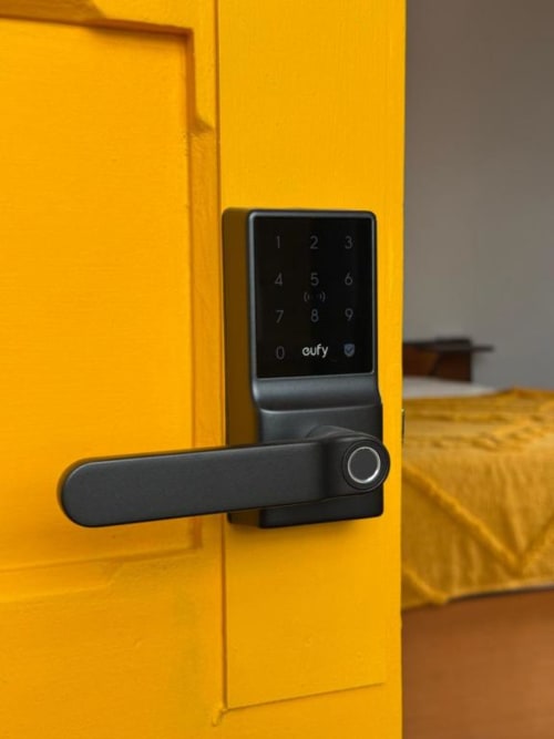 Fechadura inteligente Eufy com teclado na porta amarela da Golden Mermaid Villa, uma pensão portuguesa com acesso seguro