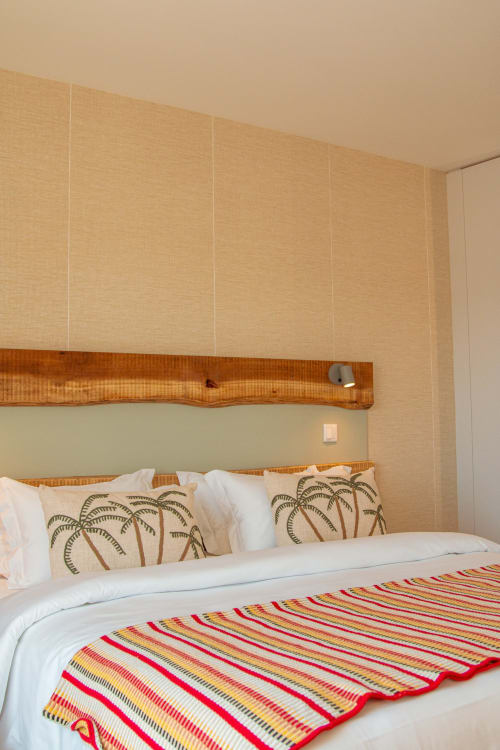 Cama com almofadas decorativas de palmeira e manta listrada no hotel M'ar Puro em Santo Isidoro