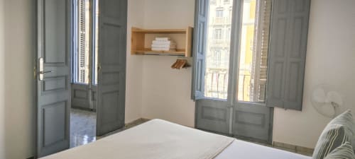 Luminoso dormitorio en apartamento BCNMADflats Barcelona Eixample con cama doble, estantería de madera, puertas balconeras azules y