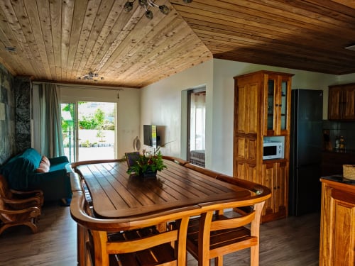 Spacieux séjour du gîte avec table de salle à manger en bois, fauteuil turquoise et vue sur les montagnes à La Kaz 57