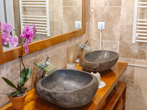 Salle de bain luxueuse avec deux vasques en pierre, meuble-lavabo en bois et murs carrelés à La Kaz 57 en Réunion