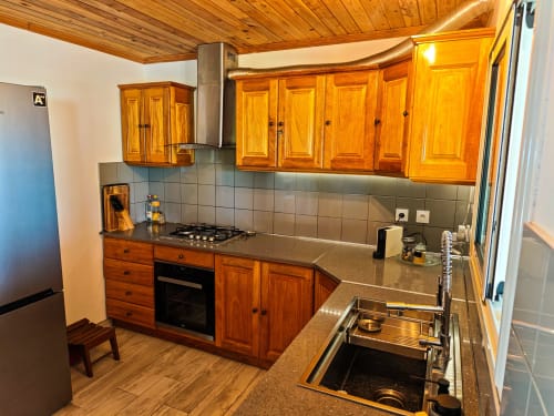 Cuisine moderne du gîte La Kaz 57 à La Plaine des Palmistes, avec meubles en bois, plan de travail foncé, cuisinière gaz et acier inoxydable