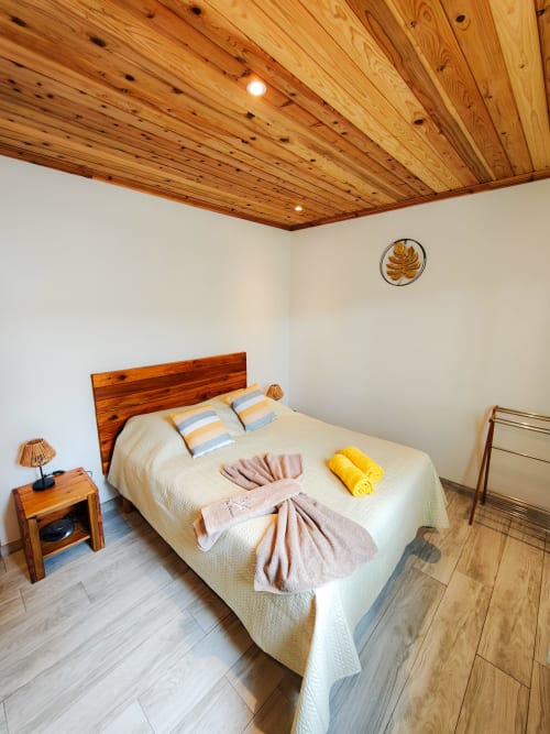 Chambre spacieuse du gîte La Kaz 57 à La Plaine des Palmistes avec plafond en bois, lit queen-size et vue sur les montagnes.