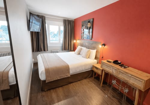 Modernes Standardzimmer im Hôtel Des Cèdres in Orleans mit Queensize-Bett, roter Akzentwand, Stadtblick und zeitgenössischem Design