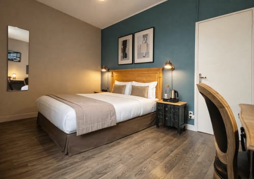 Modernes Hotelzimmer im Hôtel Des Cèdres in Orleans mit Holzbett, blaugrüner Akzentwand und Gartenblick