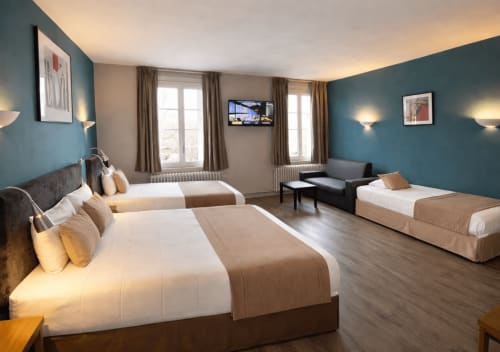 Spacieuse chambre familiale de l'Hôtel Des Cèdres d'Orléans avec plusieurs lits, murs bleus, télévision et vue sur la ville