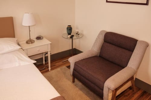 Quarto duplo padrão na Quinta de Anterronde com cama, poltrona, criado-mudo com luminária e assoalho de madeira