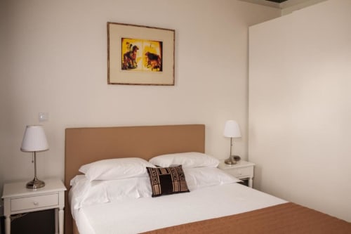 Quarto duplo padrão da Quinta de Anterronde com vista para a montanha, roupa de cama branca, cabeceira castanha e dois abajures.