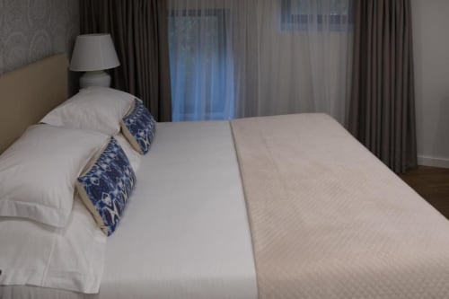 Cama luxuosa na Quinta de Anterronde com almofadas azuis estampadas, lençóis brancos e cortinas com vista para o rio