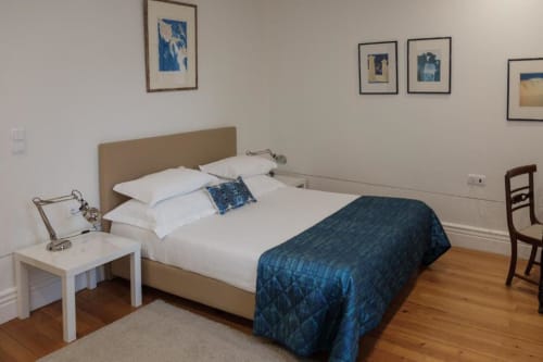 Espaçoso quarto superior triplo na Quinta de Anterronde com cama queen, roupas brancas, colcha azul e piso em madeira.