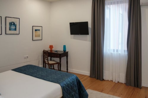 Quarto luminoso na Quinta de Anterronde com cama, secretária, TV, pisos de madeira e decoração moderna