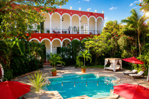 Piscina del patio de Villa Merida con arcos rojos, jardines tropicales y áreas de descanso en Mérida, México