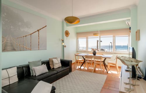 Bright ocean view apartment in Charneca da Caparica with black sofa, dining table, and sea views through large windows