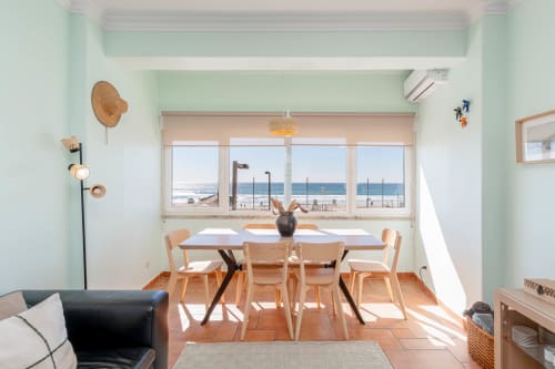 Bright sea-view apartment dining area with ocean views, wooden furniture, and modern amenities in Charneca da Caparica