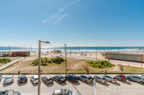 Parked cars along beachfront at Republica do Sul hotel in Charneca da Caparica, Portugal, with sandy beach and sea view