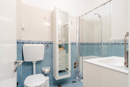 Modern bathroom with blue and white tiles, toilet, shower enclosure, and bathtub in Ocean apartment at Republica do Sul,