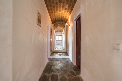 Corredor em arco de tijolos com paredes brancas e portas de madeira na quinta Vale Clara em Alandroal, Portugal
