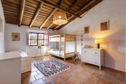 Espaçoso quarto de villa no Alentejo com teto de vigas de madeira, camas beliche, azulejos em terracota e decoração rústica no hotel Vale Clara