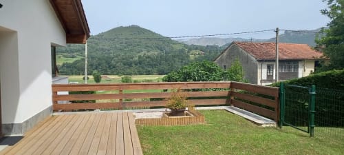 Terraza de madera con barandilla con vistas al valle verde y montañas en El Respigu, Cangas de Onís