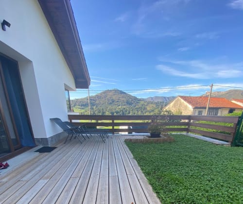 Terraza de madera con hamaca reclinable con vistas al jardín verde y montañas en Apartamentos El Respigu, Cangas de Onís