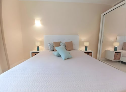 Quarto moderno do apartamento Sweet Home Litoral Mar em Portimão com cama branca, almofadas azuis e vista para o mar