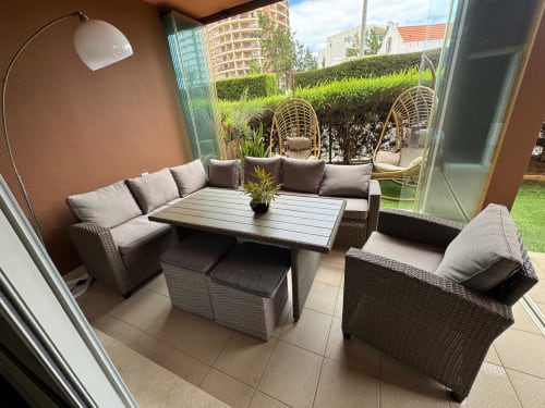 Pátio do apartamento em Portimão com mobiliário em vime, vista para o mar e acesso ao jardim na Sweet Home Litoral Mar