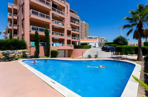 Piscina azul do Sweet Home Litoral Mar em Portimão com vista para o mar e edifício residencial rosa