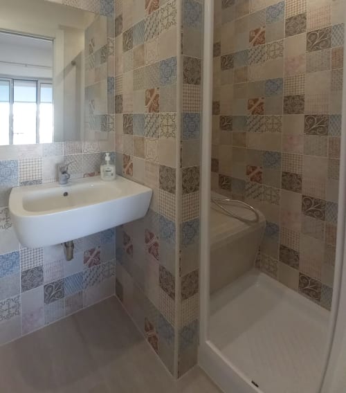 Modern bathroom with patterned tile walls, white sink, and shower at L'attico di Matilde in Siracusa, Sicily