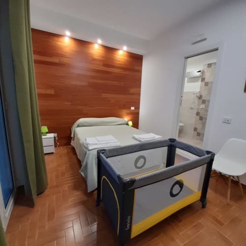 Camera da letto moderna in L'attico di Matilde a Siracusa con parete in legno, letto, culla e bagno ensuite