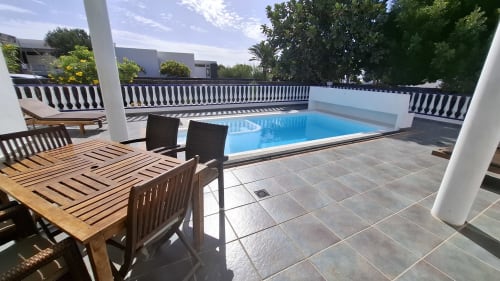 Private pool terrace at Villas del Mar in Puerto Calero with loungers, dining area, and blue swimming pool overlooking