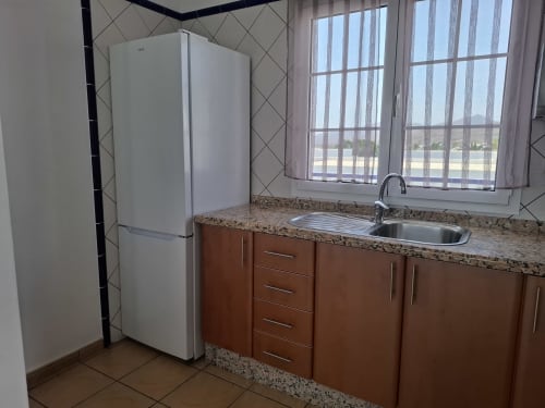 Modern kitchen in Villa 8 at Villas del Mar with white refrigerator, granite countertop, sink, and mountain views through