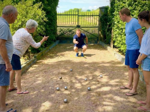 Family playing pétanque on sandy court at Le Clos Des Anges, Bagnols France