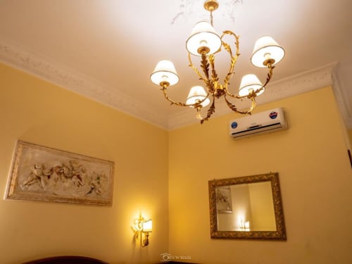 Elegante camera gialla presso Alla Basilica Rooms con sfarzoso lampadario in oro, pannelli decorativi in rilievo e specchio incorniciato a San
