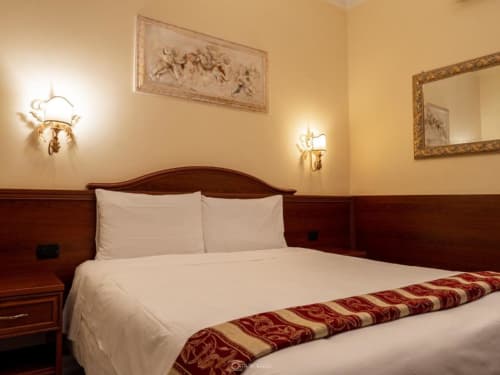 Camera elegante presso Alla Basilica Rooms a San Giovanni con letto in legno, biancheria bianca e arte classica alle pareti
