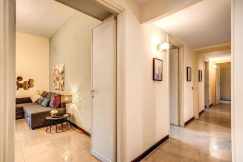 Corridoio di appartamento moderno a Roma con più porte, illuminazione calda, pavimenti in piastrelle e accogliente angolo di seduta