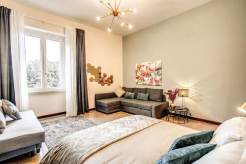 Appartamento Borghese verde a Roma con camera da letto matrimoniale, divano grigio, finestra con vista sul giardino e design moderno
