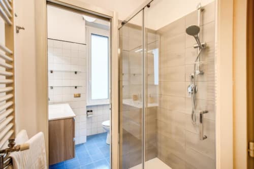 Bagno moderno in appartamento verde Borghese con doccia in vetro, piastrelle bianche, pavimento blu e toilet a Downtown Srl