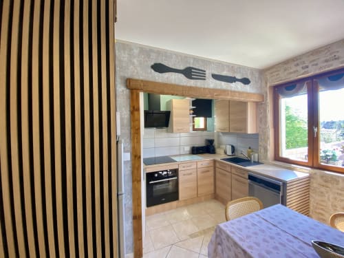 Cuisine moderne avec meubles en bois, électroménagers noirs et coin repas à la villa Le Petit Prince d'Ô Clair De Lune, Sarlat