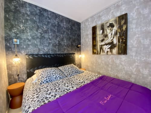 Chambre douillette de la villa Le Petit Prince à Sarlat avec literie à motifs, plaid violet et murs texturés foncés