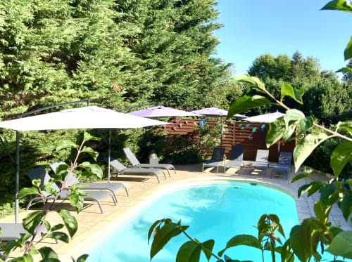 Zone piscine ensoleillée aux eaux turquoise, transats, parasols et verdure luxuriante à la villa Ô Clair De Lune à Sarlat