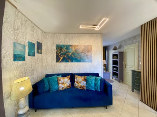 Salon moderne avec canapé bleu marine, accents turquoise et œuvres d'art au cottage Le Petit Prince à Sarlat, France