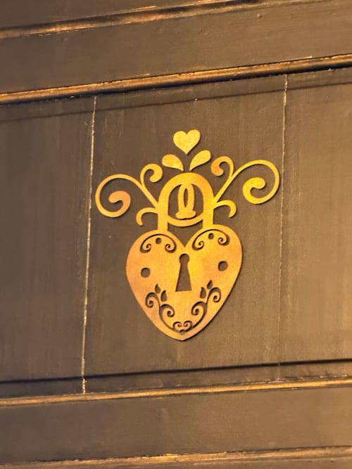 Cadenas doré en forme de cœur orné de motifs décorés sur la porte en bois sombre de La Maison Defendue
