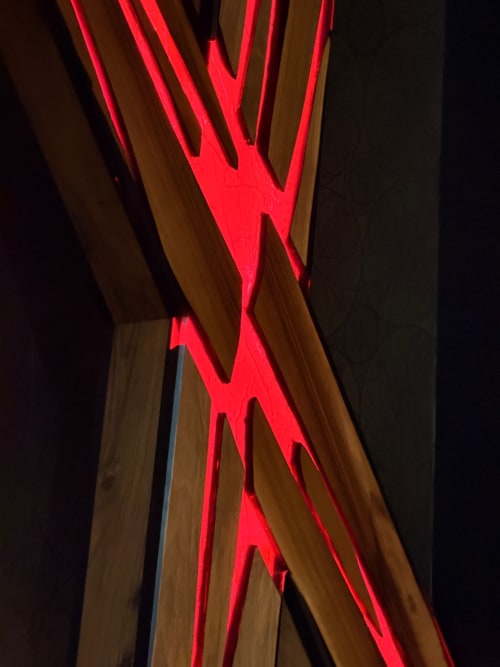 Enseigne néon rouge luminescente « W » fixée sur des poutres en bois à La Maison Defendue, appartement à Tessy-Bocage, France