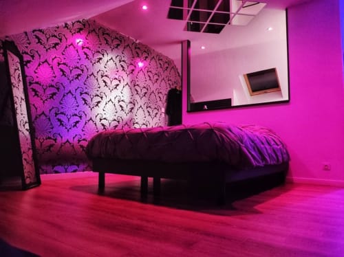 Chambre moderne aux néons magenta, lit noir et mur d'accent à motifs ornementaux à La Maison Defendue, Tessy-Bocage