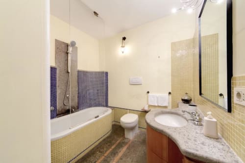 Bagno moderno con piastrelle gialle, lavabo, wc, vasca con particolari blu presso The Smart Loft a Roma