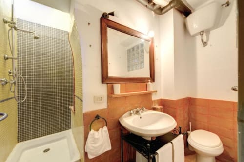 Bagno con lavabo rotondo, specchio, wc e doccia con piastrelle verdi nell'appartamento Smart Loft di Downtown Srl Roma